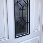 Porte en PVC blanc, avec panneaux à facette et grille imitation fer forgé